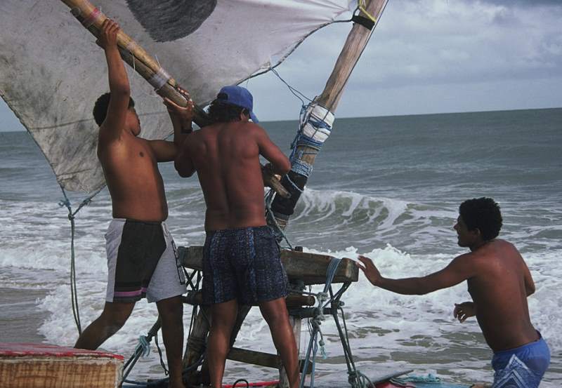 Two jangadeiros placing the boom head on the mast.