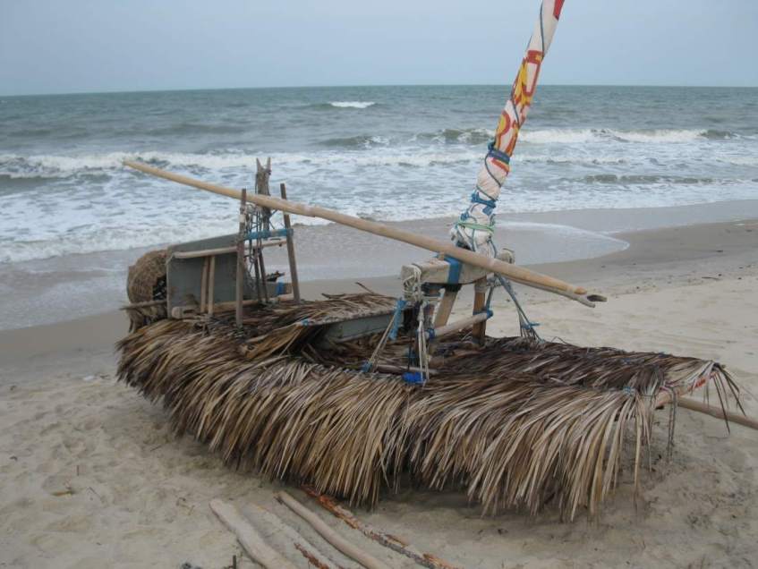 A jangada on the beach, its deck covered with palm fronds to protect against the hot sun.